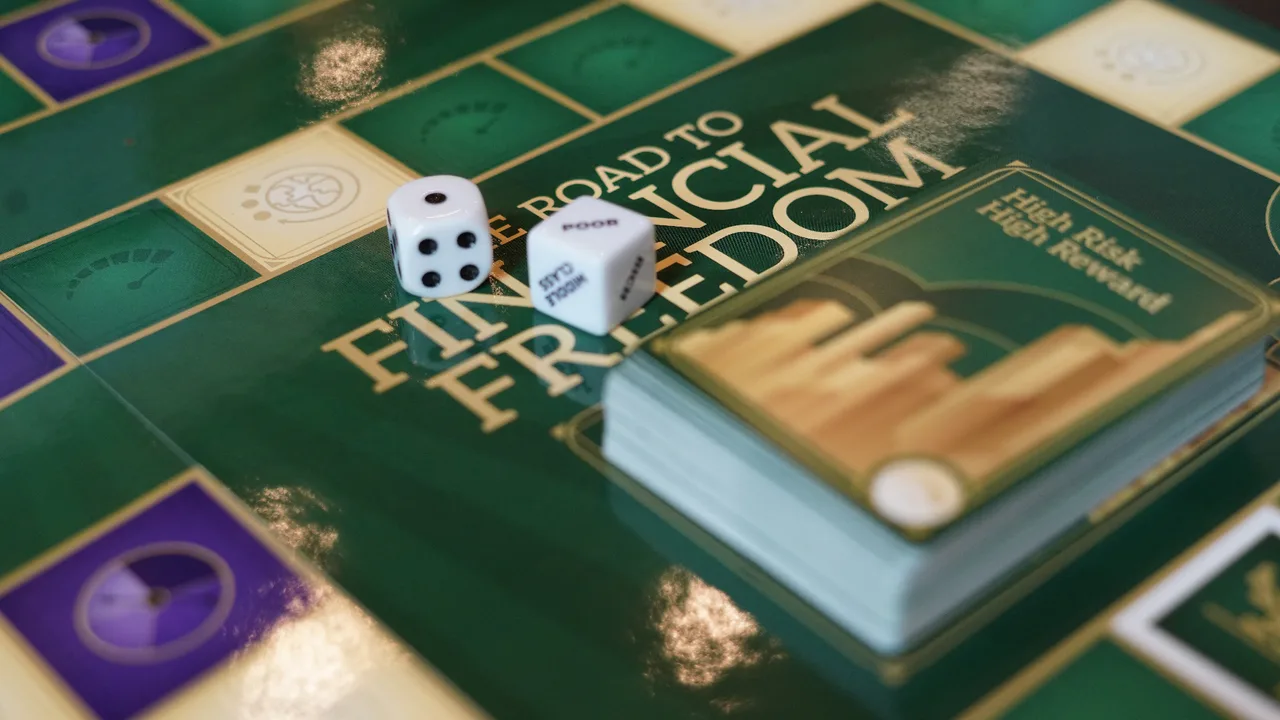 Close-up of The Road to Financial Freedom game board with dice and cards mid-play