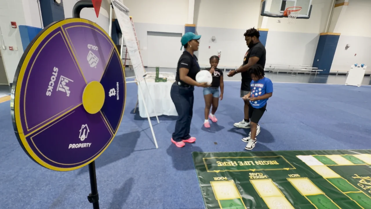 16 WAPT segment preview: students at the life-sized Road to Financial Freedom game with the spinning wheel